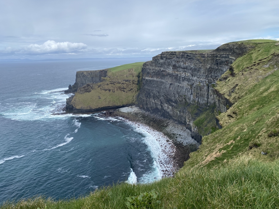 Vue aérienne de falaises côtières avec des vagues qui se brisent en contrebas.