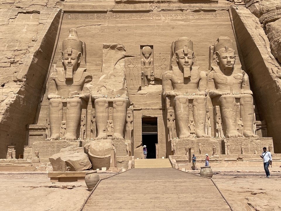 Vue de face d'Abou Simbel avec d'énormes statues et des touristes.