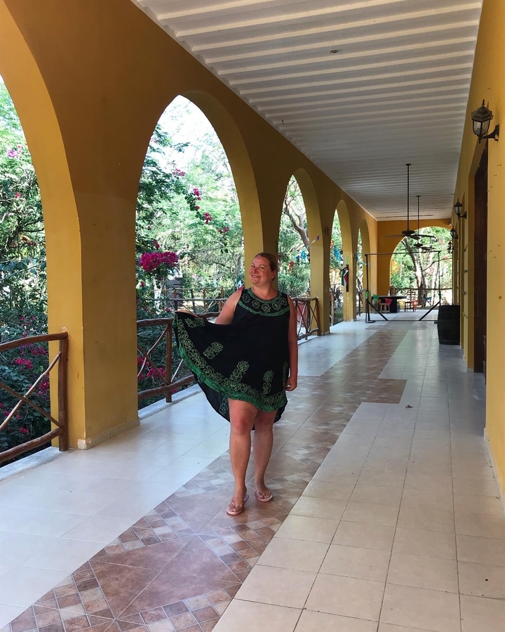 Person in a dress posing in a corridor with arches.