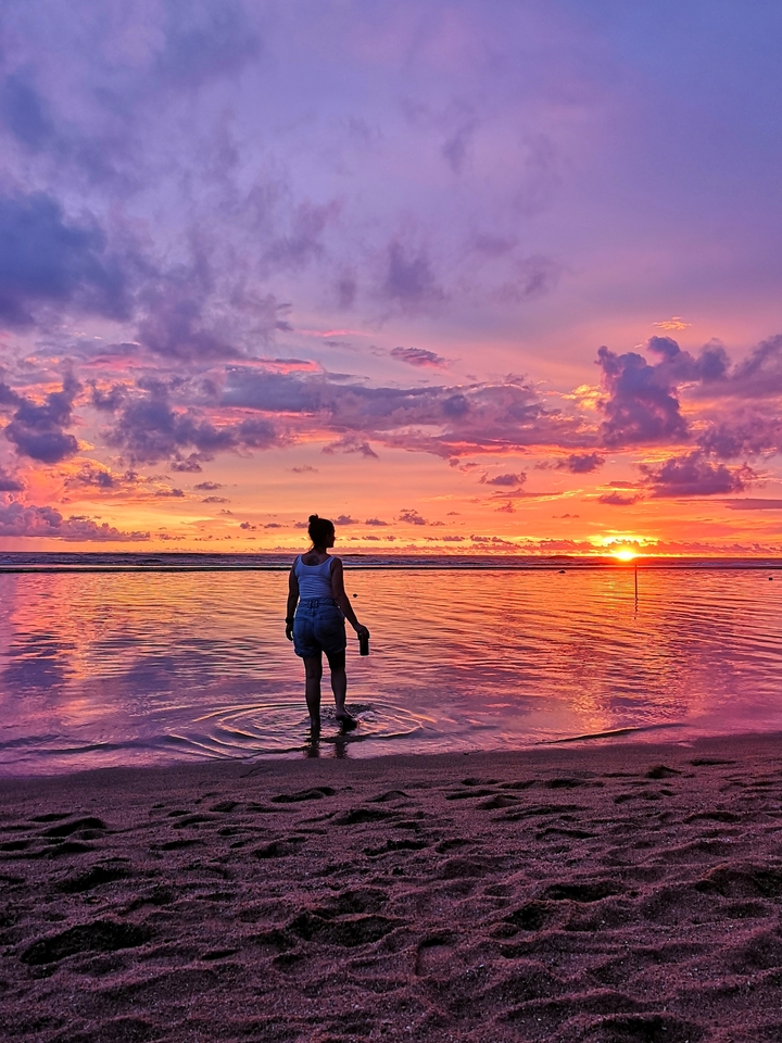 Personne marchant dans l'eau peu profonde pendant un coucher de soleil éclatant