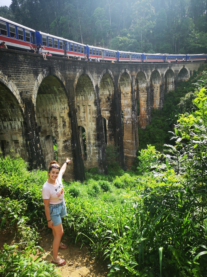 Personne pointant du doigt un pont en pierre historique