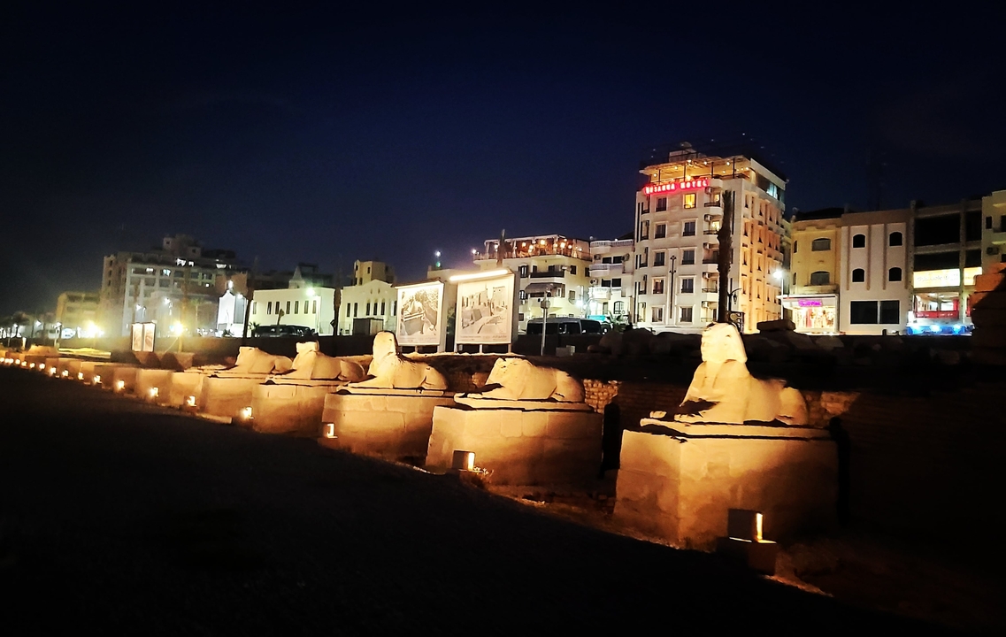Statue-lined avenue at night.