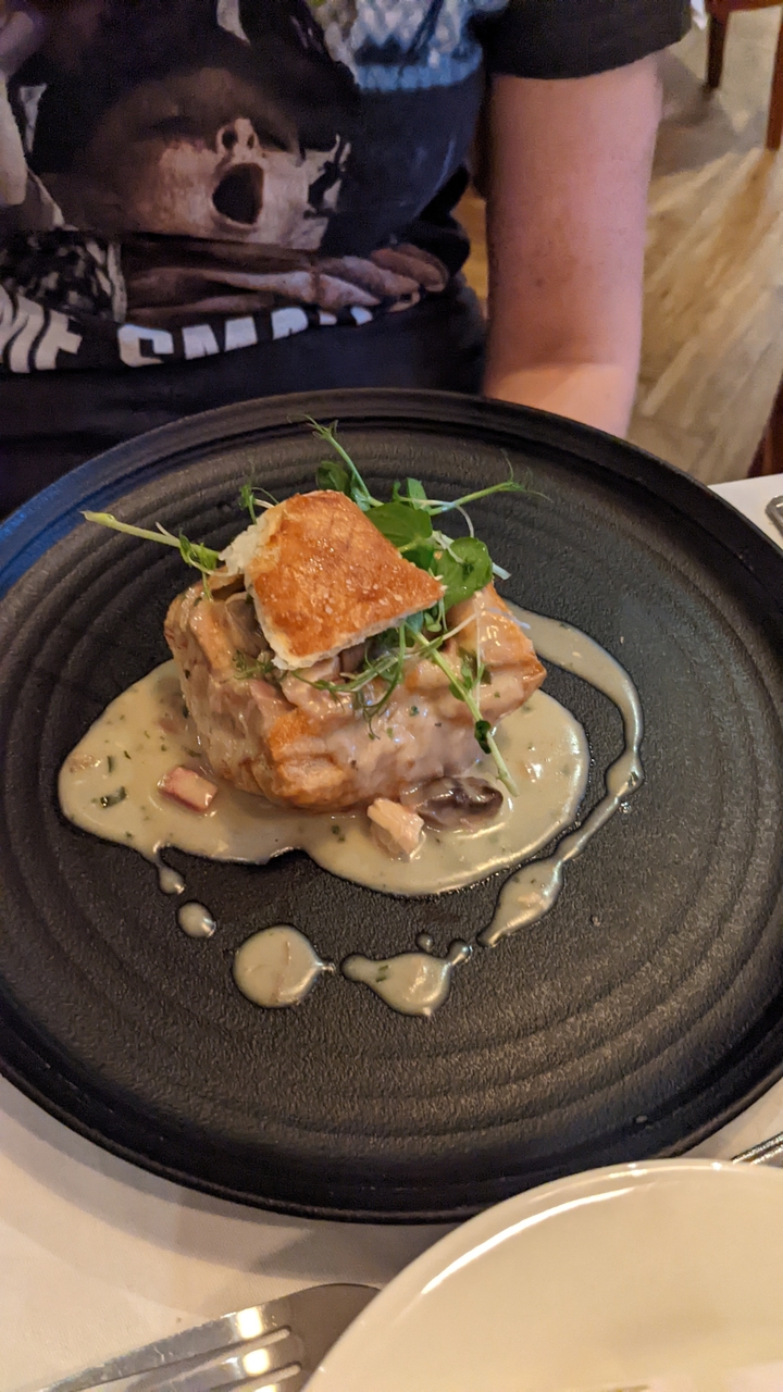 Un plat avec de la pâte feuilletée et une sauce crémeuse garni de verdure.