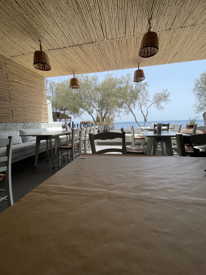 Café avec tables et chaises donnant sur une vue mer.