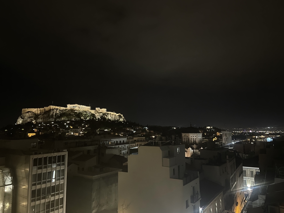 Vue nocturne de l'Acropole illuminée au-dessus d'Athènes.