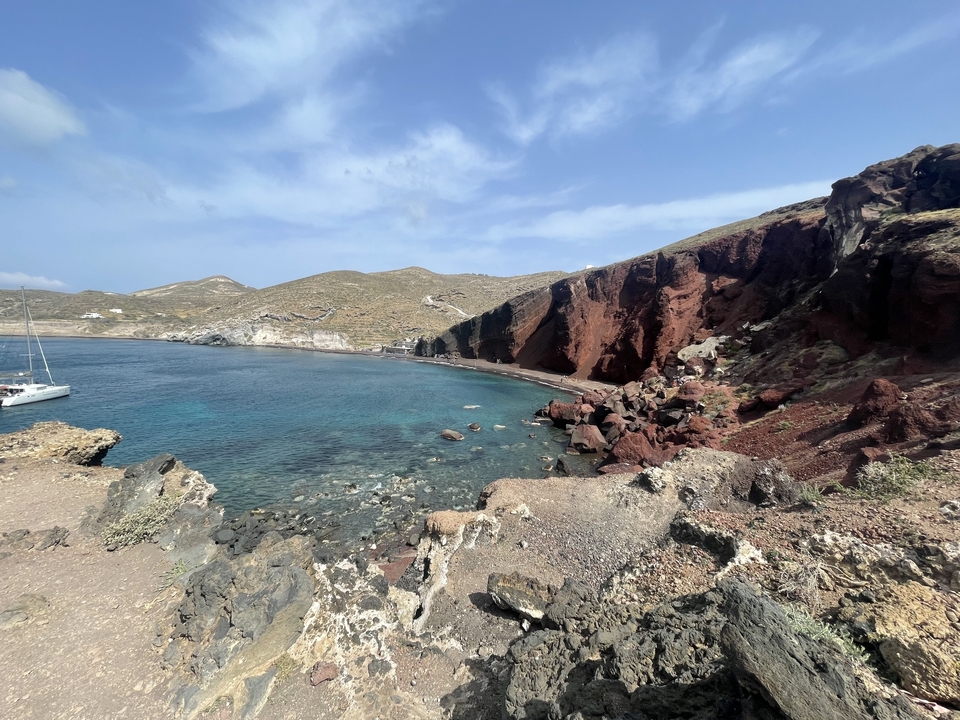 Une côte rocheuse avec une eau claire et un bateau au loin.
