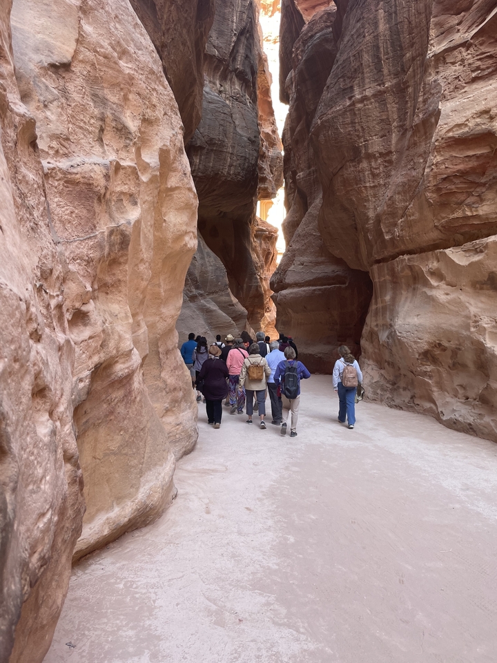Un groupe de touristes marchant à travers une gorge étroite avec de hautes parois rocheuses.