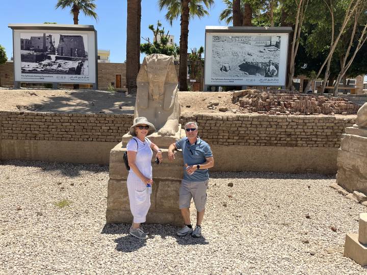 Deux personnes debout à côté d'une statue avec des images historiques en arrière-plan.