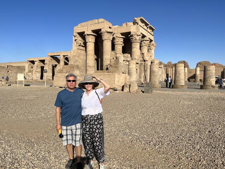 Deux personnes posent devant les ruines du temple de Kom Ombo avec un ciel bleu clair.
