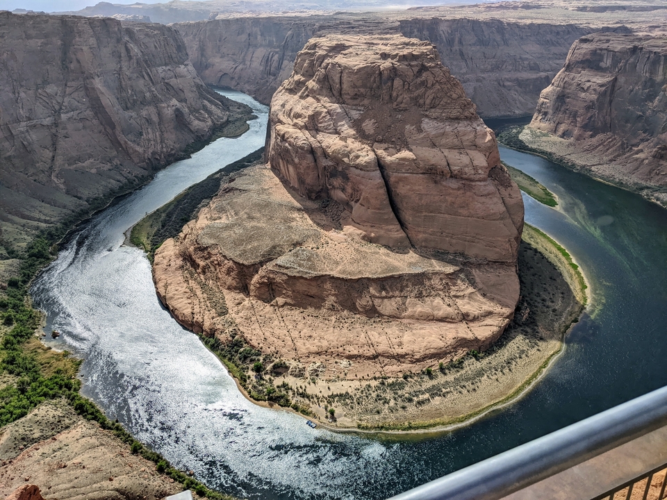 Vue panoramique d'un méandre en fer à cheval dans une rivière avec des falaises escarpées.