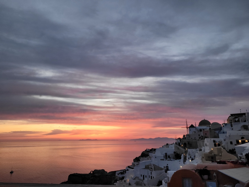 Coucher de soleil coloré au-dessus de maisons blanches sur une falaise.