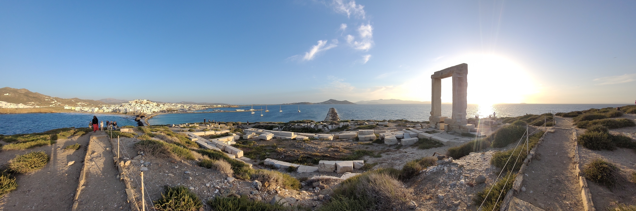 Vue panoramique de ruines au bord de la mer avec des bateaux amarrés.