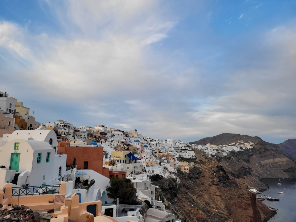 Village coloré sur une falaise sous un ciel nuageux.