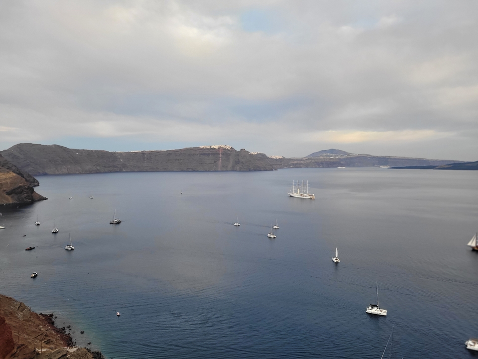 Des bateaux sur une large baie, entourée de falaises et de montagnes.