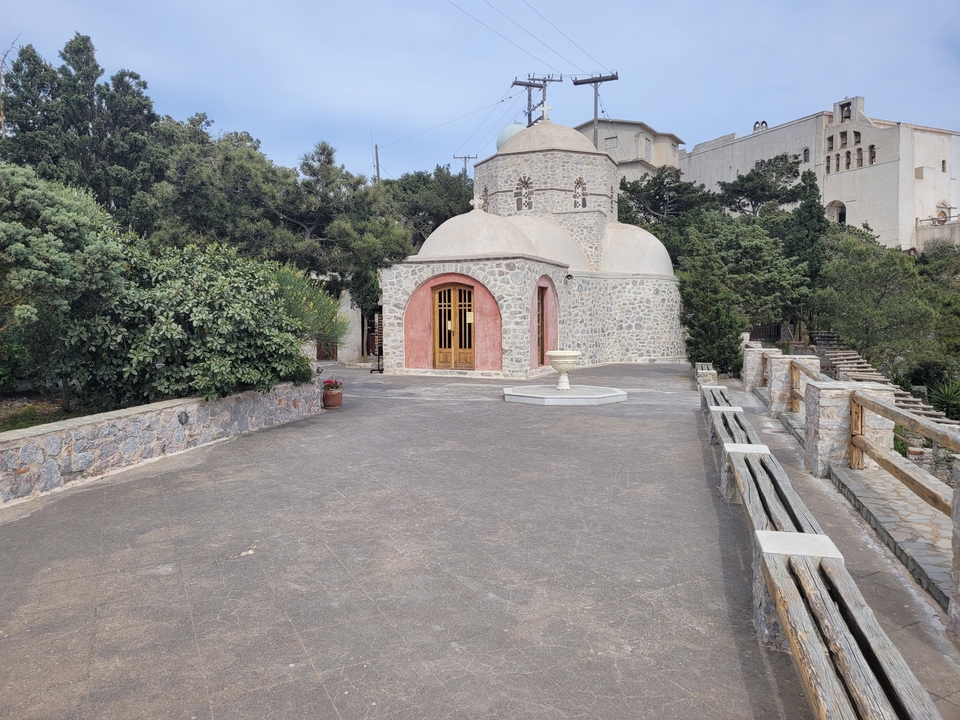 Bâtiment en pierre avec toit de tuiles entouré d'arbres.
