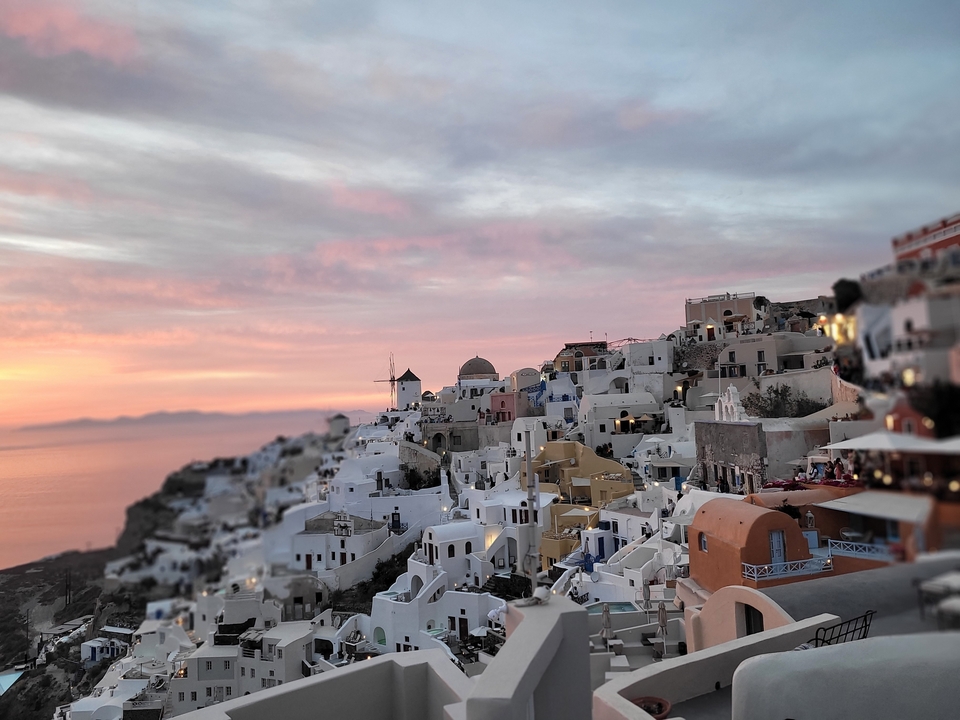 Maisons construites sur une colline escarpée, ciel aux couleurs du coucher de soleil.