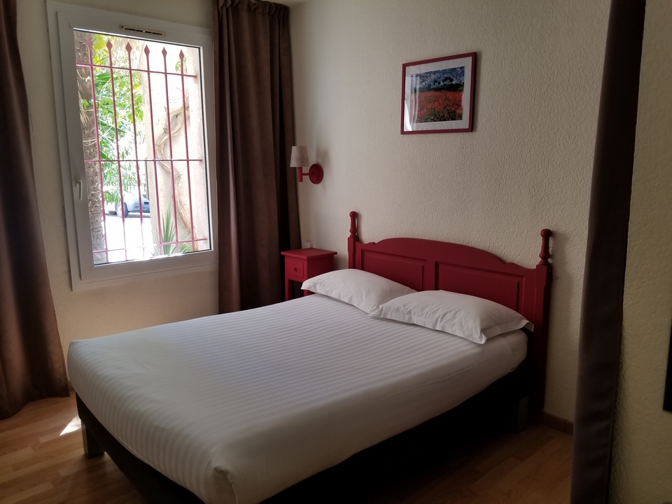 Une chambre d'hôtel simple avec un lit près d'une fenêtre.