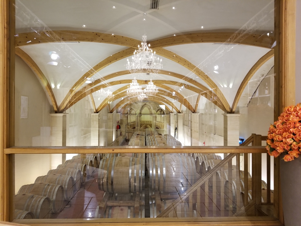 Intérieur d'une cave à vin avec des tonneaux et des lustres.