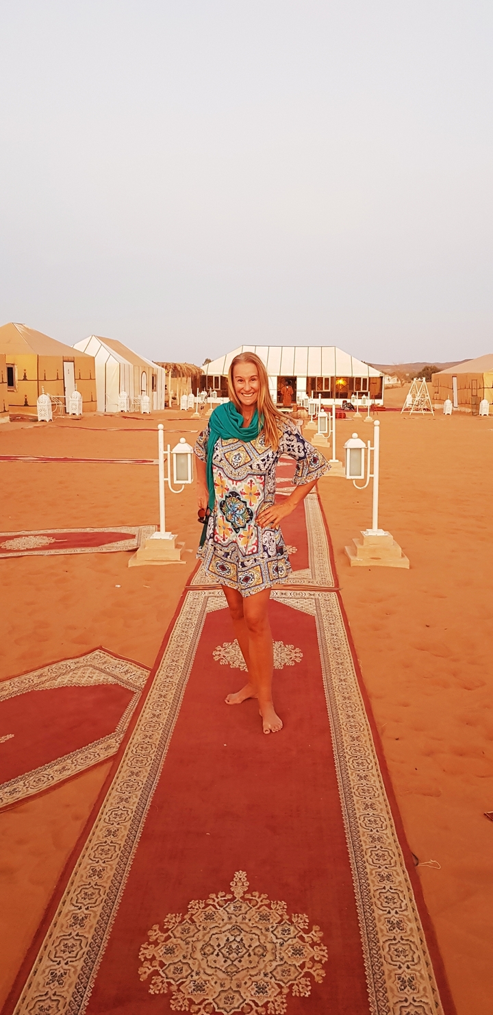 Femme souriante debout sur un sentier décoré dans un camp du désert.