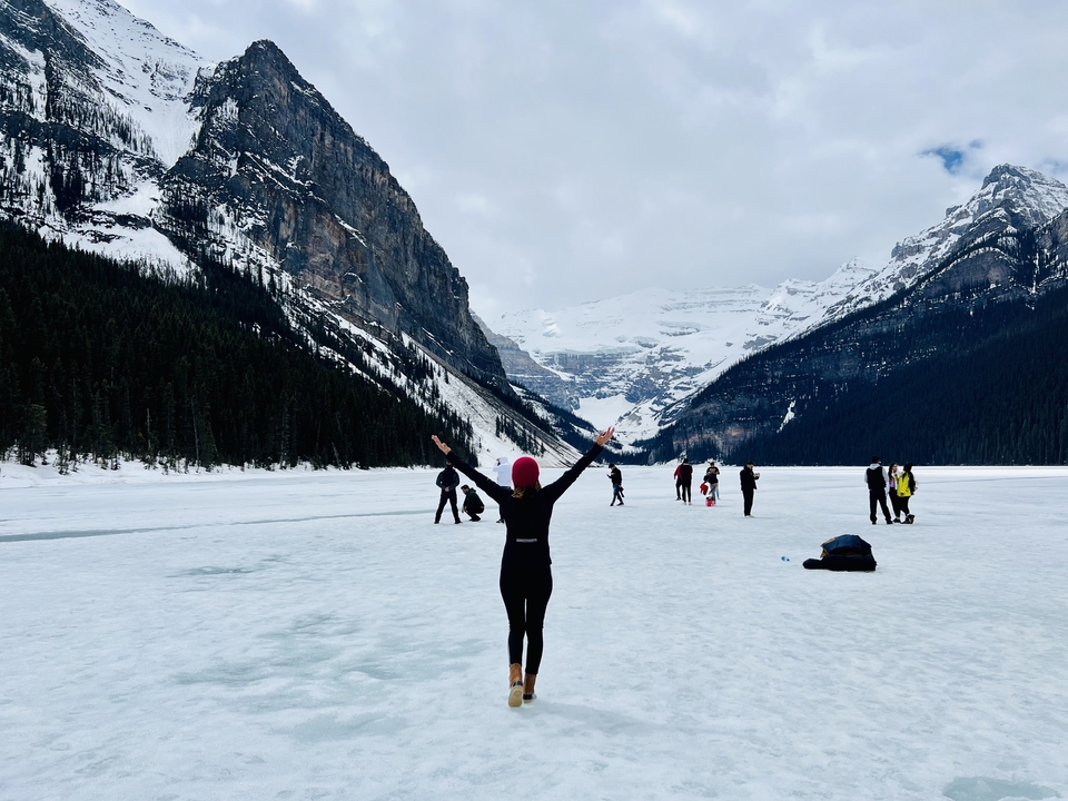 Des gens qui profitent du terrain enneigé près d'un lac gelé au milieu des montagnes.