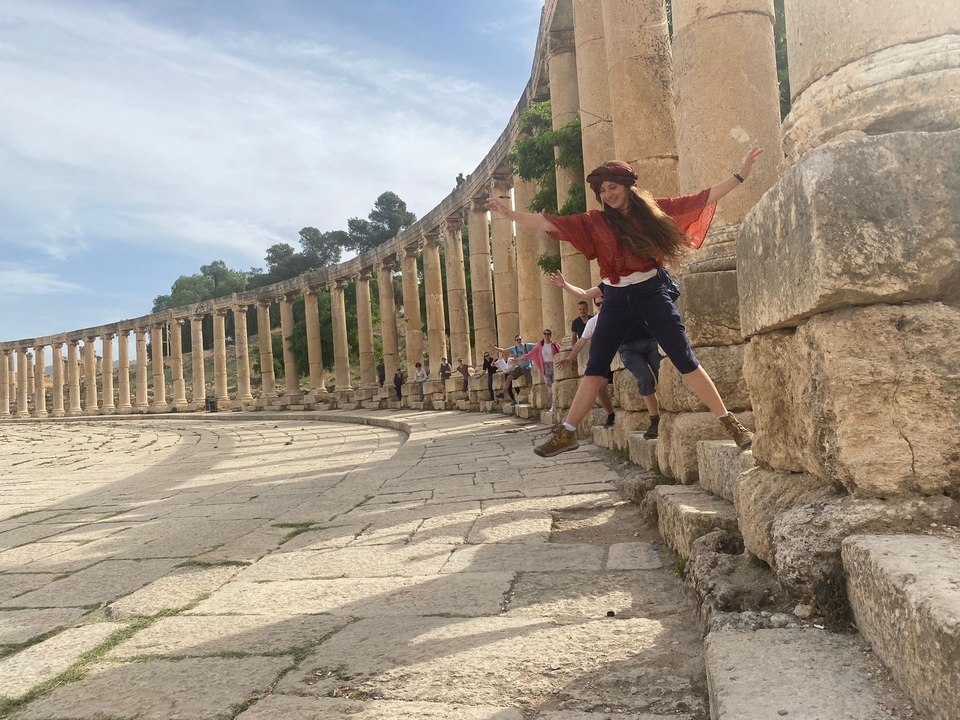 Personne sautant au premier plan d'une colonnade antique.