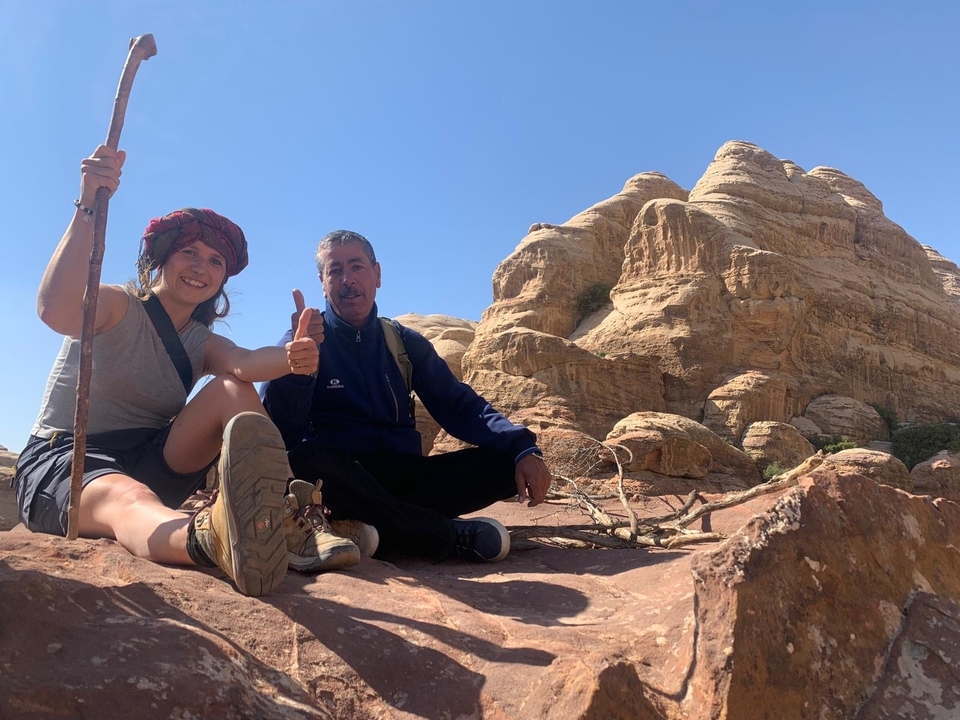 Deux personnes assises sur des rochers avec un paysage désertique en arrière-plan.