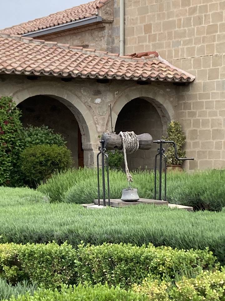Jardin avec un puits décoré de cordes.