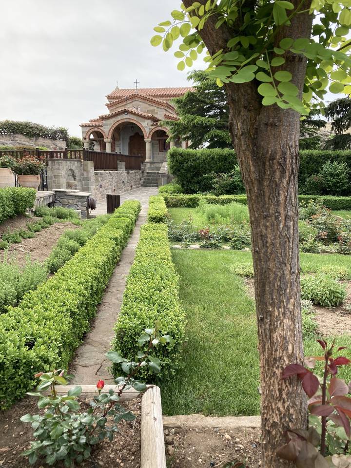 Sentier de jardin bien entretenu bordé de haies, menant à un bâtiment traditionnel.