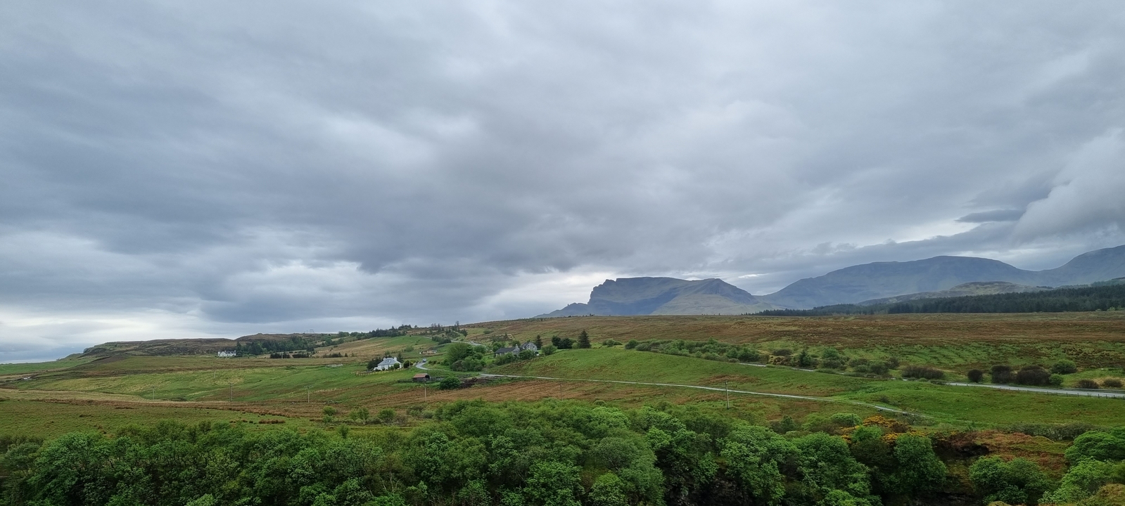 Vue panoramique d'un paysage avec des maisons dispersées et des collines.