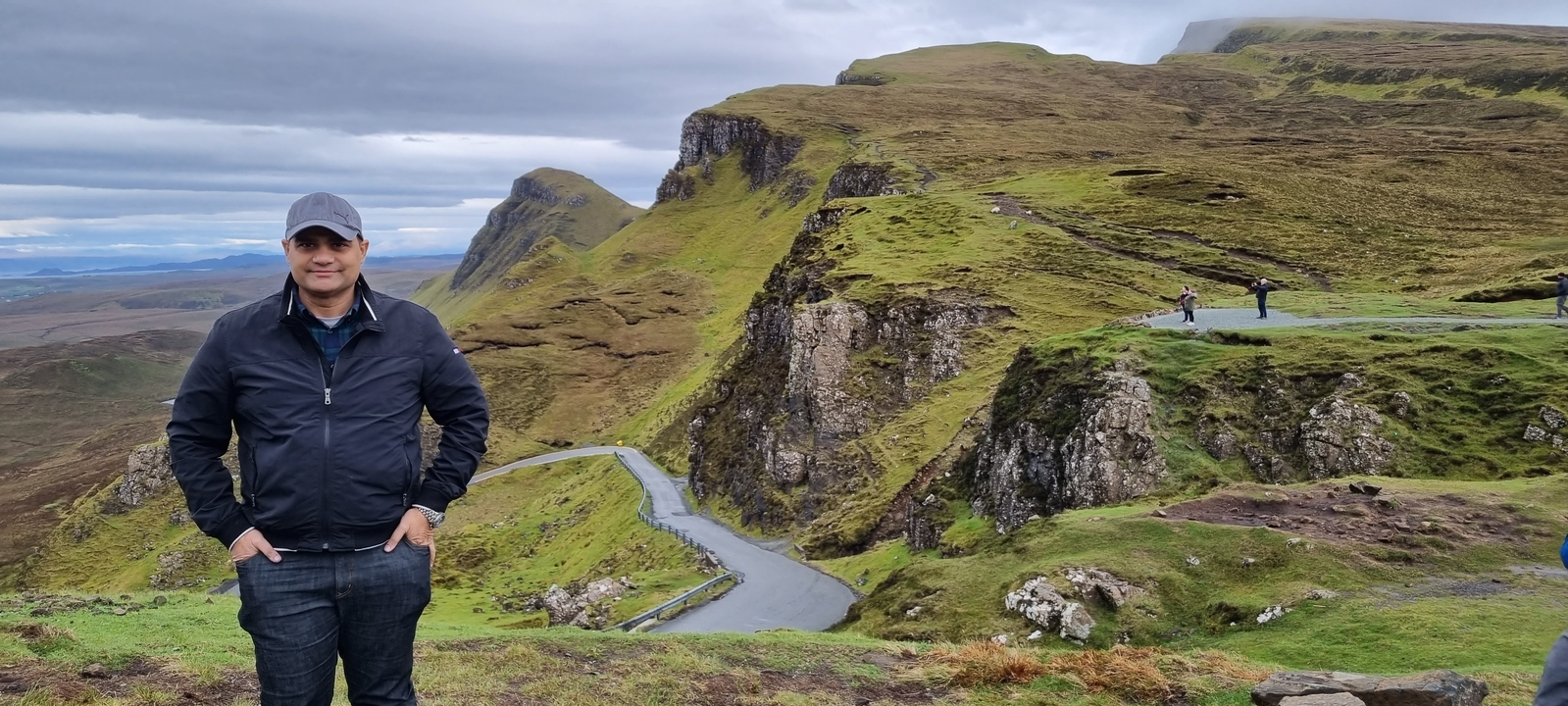 Randonneu·r·se debout sur une route sinueuse avec des falaises en arrière-plan.