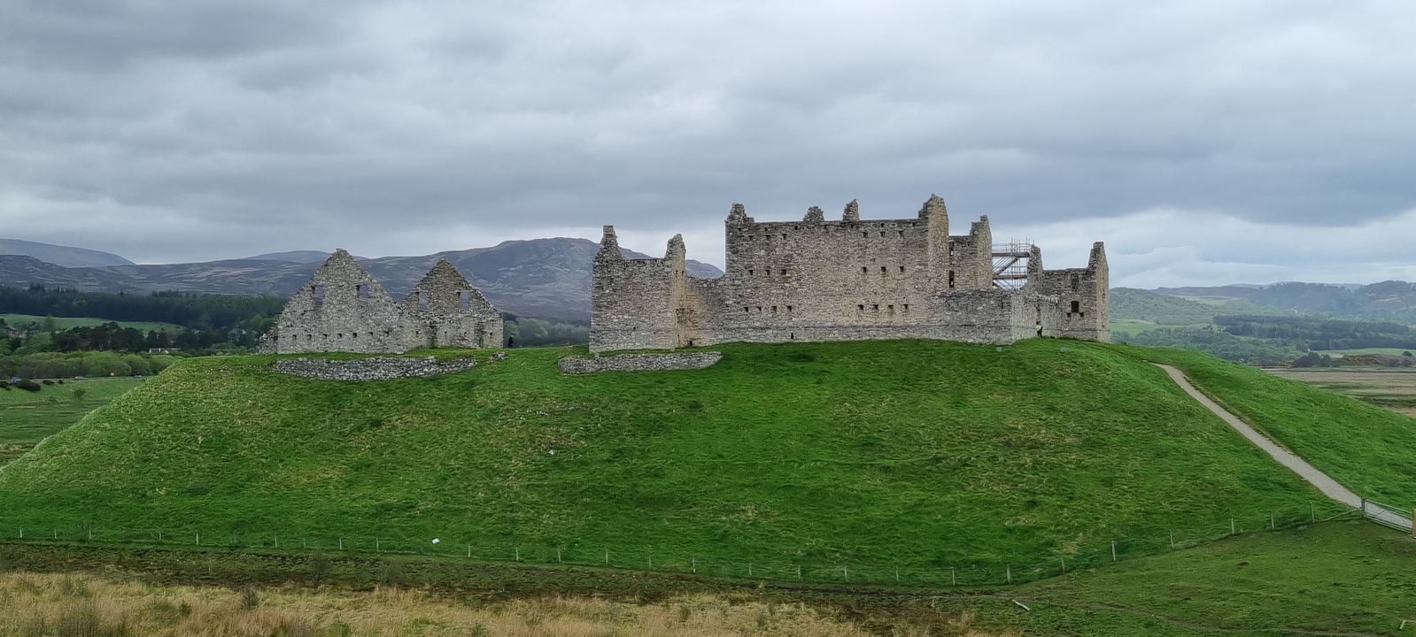 Ruines d'un château historique sur une colline herbeuse.