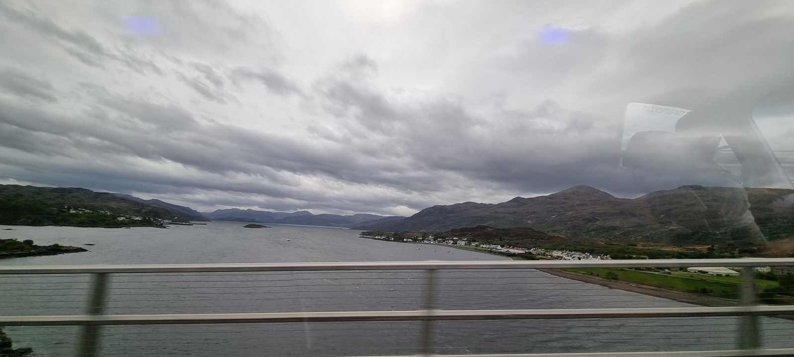 Vue d'un pont enjambant une voie d'eau avec des montagnes au loin.