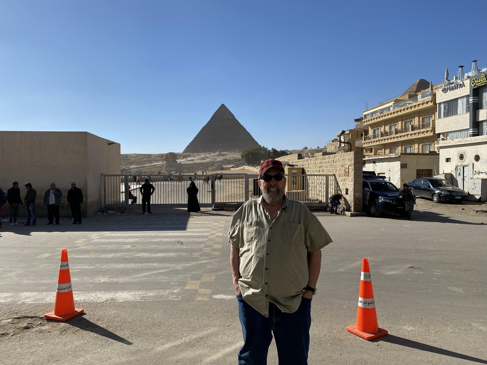 Homme debout devant la pyramide dans une zone désertique.