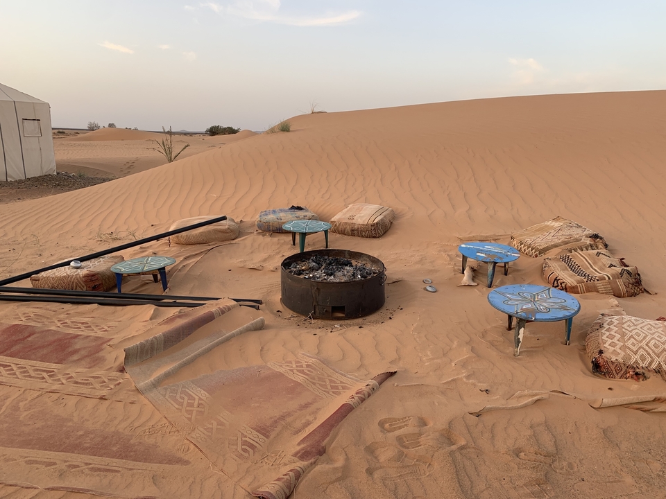 Scène de désert avec coin salon et tapis sur les dunes de sable.