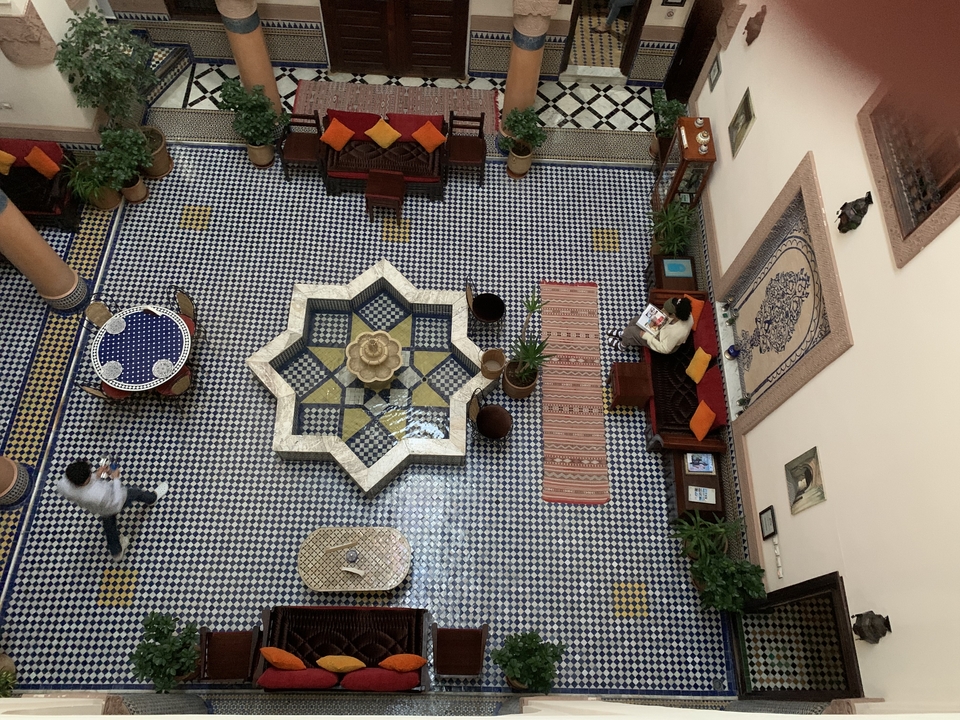 Cour traditionnelle marocaine avec sols carrelés et une fontaine.