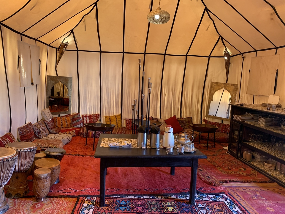 Intérieur d'une tente marocaine traditionnelle avec tapis et décorations.