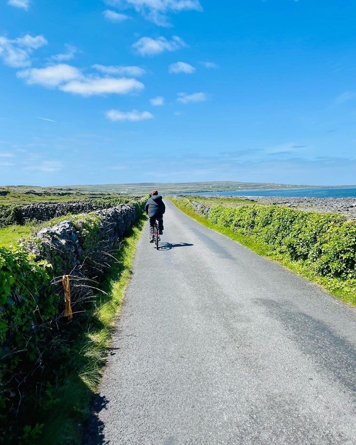 Personne faisant du vélo sur une route avec des murs de pierre et vue sur l'océan