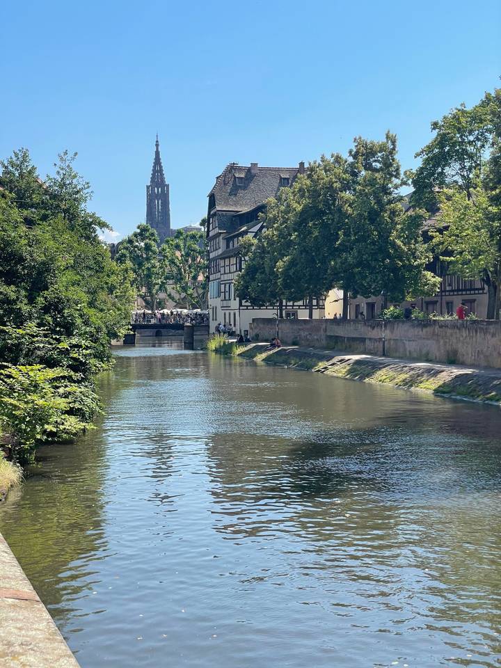 Bâtiment historique près d'une rivière entouré d'arbres.