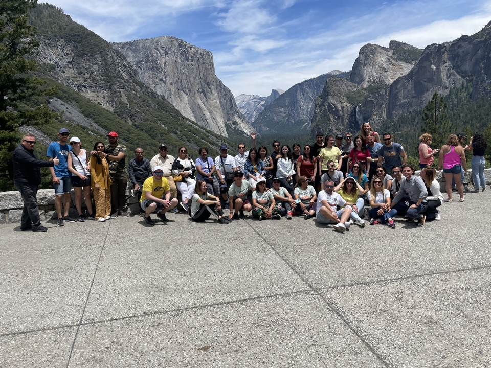 Un grand groupe de personnes posant devant un paysage montagneux.