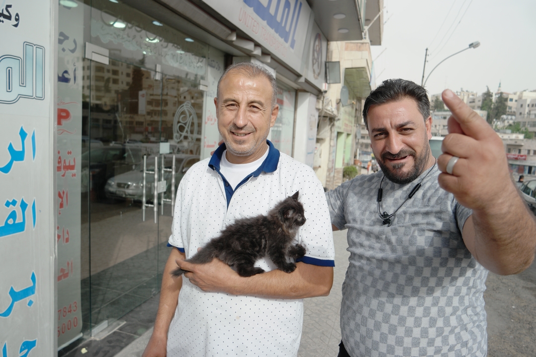 Deux hommes avec un chaton dans une zone urbaine.