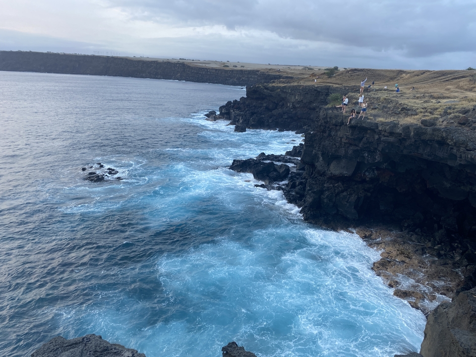 Sauteurs de falaise près d'une côte rocheuse aux eaux océaniques bleues.