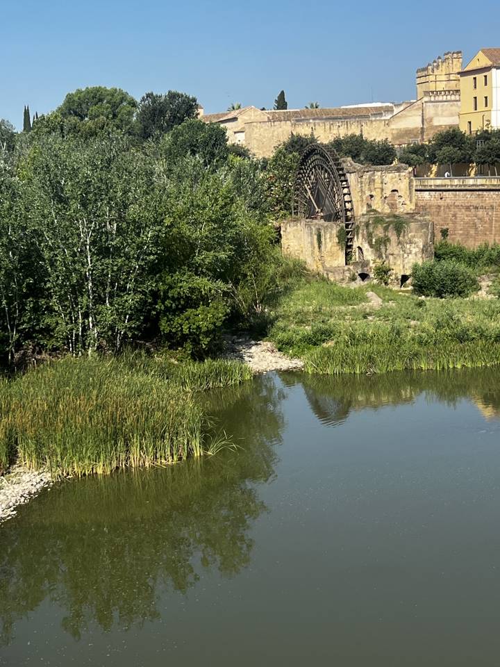 Une ancienne roue à eau en pierre et un bâtiment au bord d'une rivière.