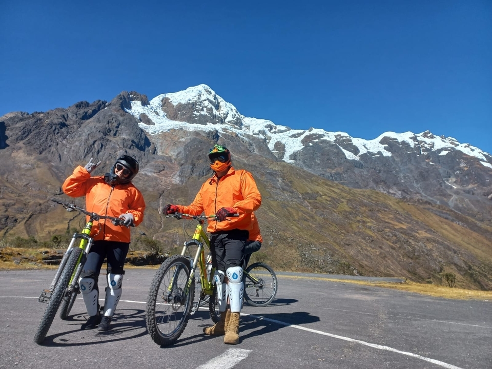 Des vététistes qui posent avec des montagnes enneigées en arrière-plan.