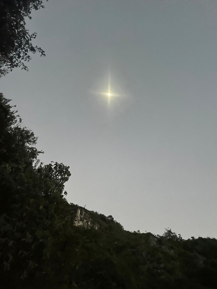 Lumière vive dans le ciel du soir au-dessus d'un paysage en silhouette.