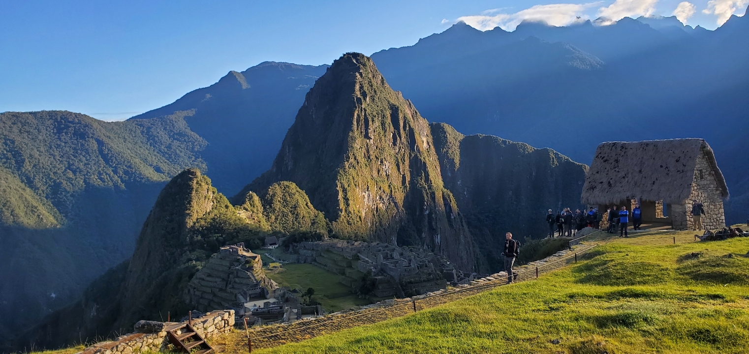 Machu Picchu avec des visiteurs et un environnement luxuriant sous un ciel dégagé.