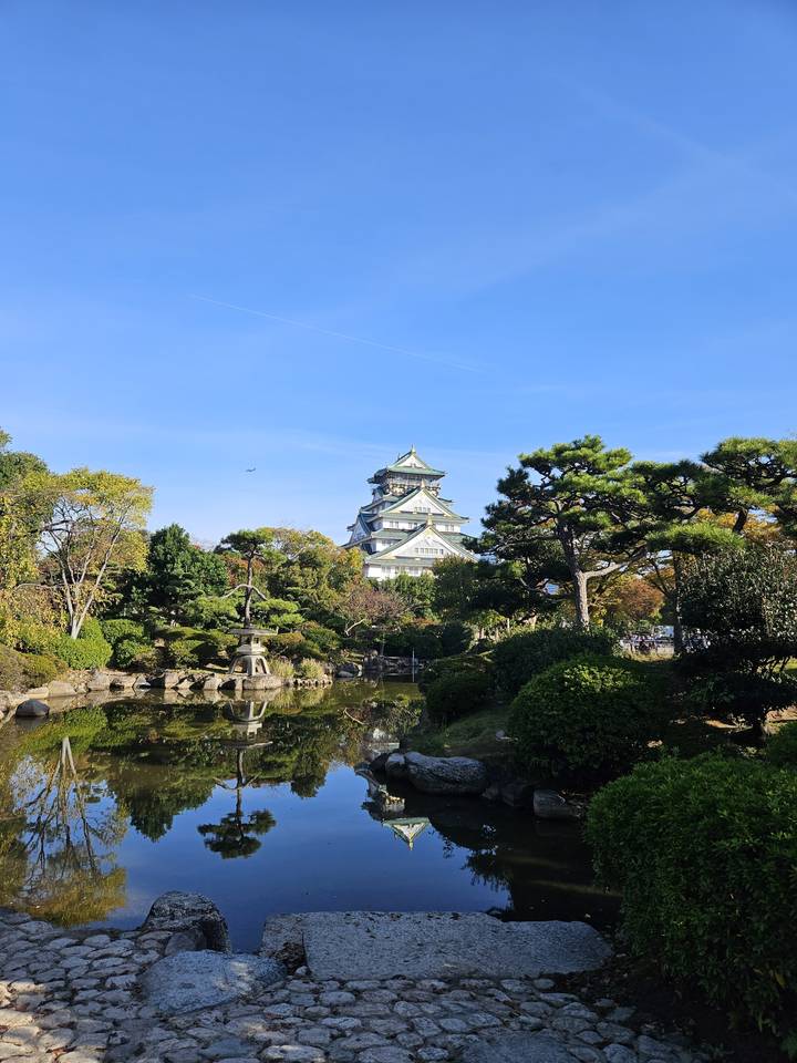 Un château avec des jardins environnants et un reflet dans l'eau.