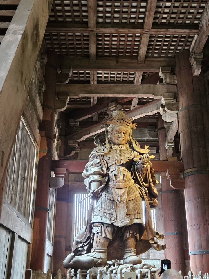 Grande statue en bois à l'intérieur d'un temple avec des détails complexes.