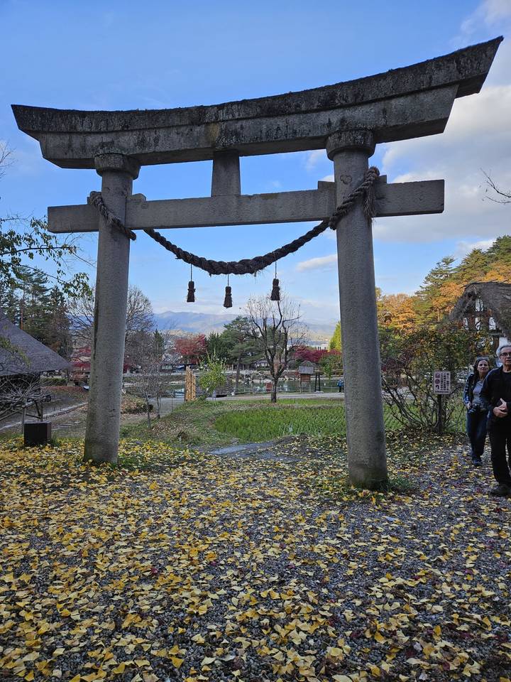 Portique torii en pierre et feuilles qui tombent dans un parc.