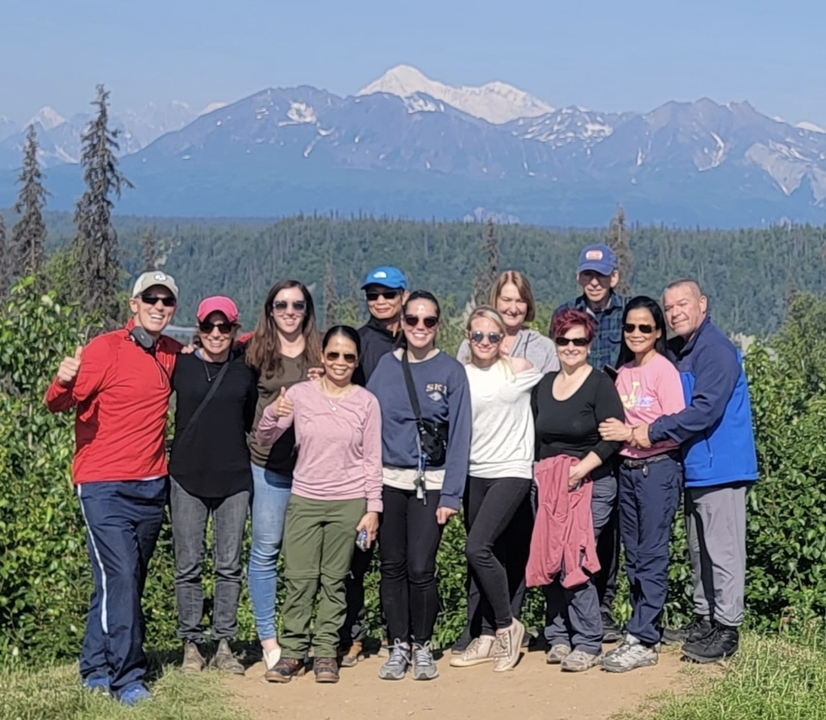 Groupe de personnes posant devant des montagnes en arrière-plan.