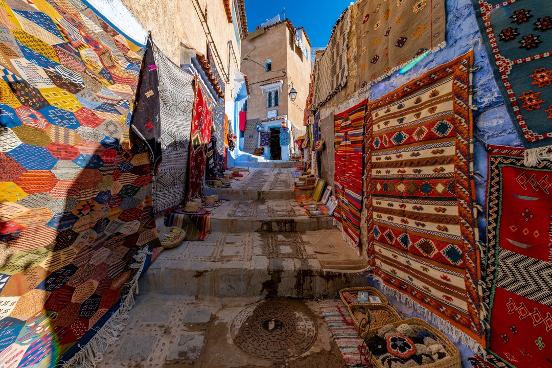 Tapis colorés et textiles exposés le long d'une rue dans une médina.